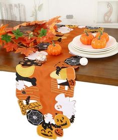 a table topped with plates and pumpkins on top of a wooden dining room table