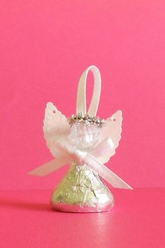 a small white angel ornament on a pink background