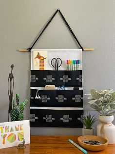 a wooden table topped with a black and white wall hanging next to a potted plant