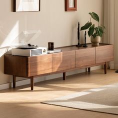 a record player sitting on top of a wooden table next to a potted plant