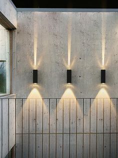 four lights are lit up on the side of a wall in front of a window