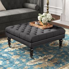 a living room scene with focus on the ottoman and coffee table in the foreground