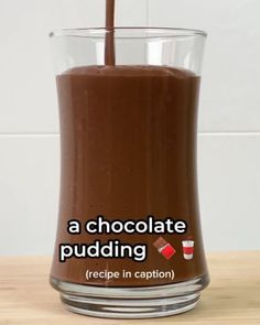 a glass filled with chocolate pudding on top of a wooden table