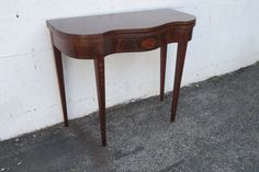 a small wooden table sitting next to a white wall on the side of a building