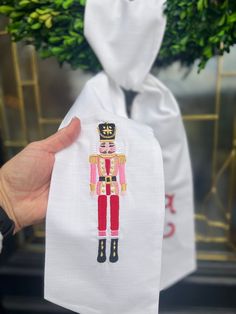 a hand holding up a white bag with a embroidered nutcracker on it