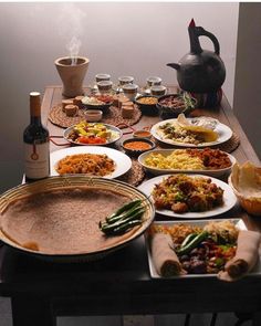 a table full of food and drinks on it with a tea kettle in the background