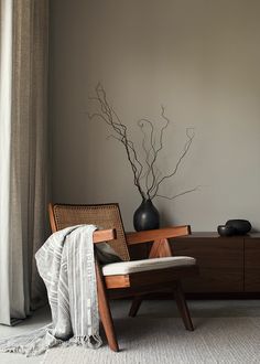 a living room with a chair, table and vase on the sideboard next to it