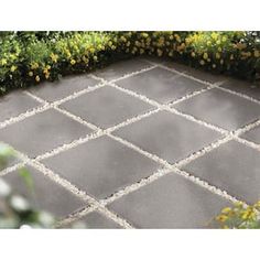 an outdoor patio with grey tiles and yellow flowers