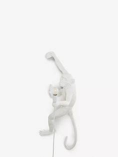 a white monkey figurine holding a light bulb on its back and standing in the air