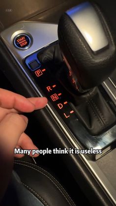 a person is pressing the button on a car's gear box with their finger