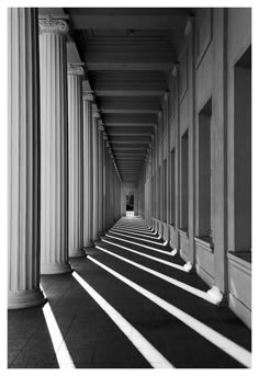 an empty hallway lined with columns and sun shining through the windows in black and white