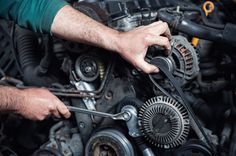 a man is working on an engine in his garage or repair shop while holding the wrench with both hands