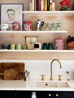 the shelves above the kitchen sink are filled with colorful vases and other decorative items