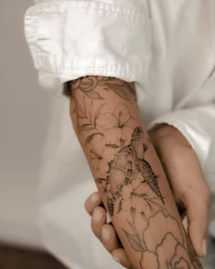 a person with a tattoo on their arm holding something in his hand and wearing a white shirt