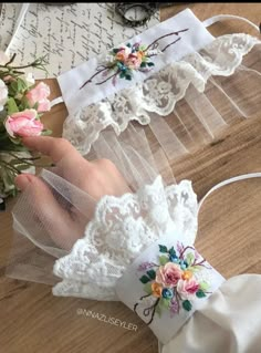 two white garters with flowers on them sitting on top of a wooden table