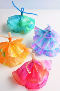 four different colored tissue paper bags with string on the top and one in the middle