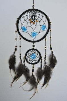 a black and blue dream catcher with feathers hanging from it's side on a white wall