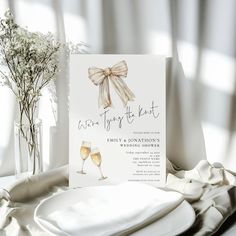 a card with a bow on it sitting next to two wine glasses and napkins