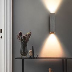 a vase with flowers on a table next to a lamp and a small teddy bear