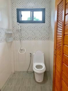 a white toilet sitting in a bathroom next to a wooden door with a window above it