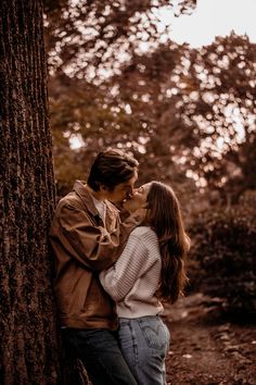 a man and woman standing next to each other near a tree