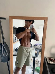 a shirtless man taking a selfie in front of a mirror with his cell phone