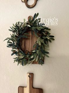 olive wreath and wooden cross hanging on the wall next to a pair of wood scissors