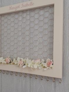 a photo frame with flowers on it hanging on a wall next to a wooden fence