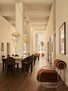 a long hallway with chairs and tables in the center, along with pictures on the walls