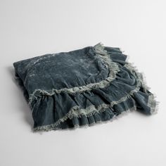 a blue blanket with ruffled edges laying on a white surface