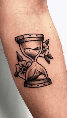 a tattoo with an hourglass and flowers on it