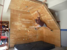 a man climbing up the side of a wooden wall