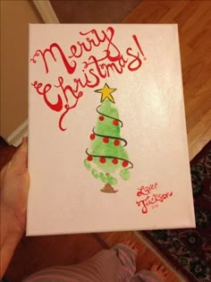 someone is holding up a christmas card with a tree on it and the words merry christmas