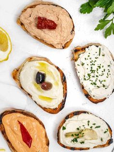 four pieces of bread with different types of food on them and garnished with olives