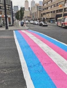 a colorful street painted with pink, blue and white stripes in the middle of a city