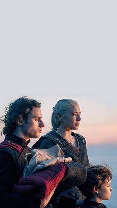 two people sitting on top of each other with the ocean and sky in the background