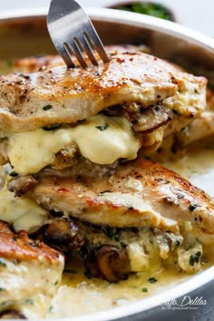 a white plate topped with chicken covered in sauce and cheese, next to a fork