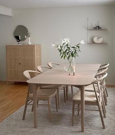 a dining room table with chairs and a vase filled with flowers on top of it