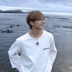 a young man standing on top of a beach next to the ocean with his hands on his hips