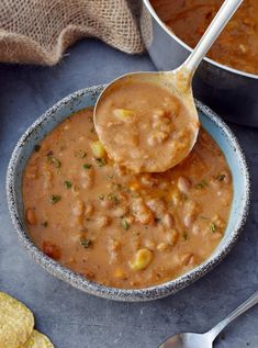 two bowls filled with beans and tortilla chips next to a pot of soup