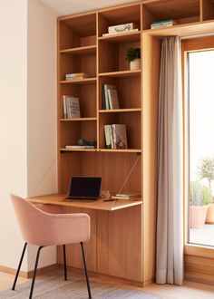 a laptop computer sitting on top of a wooden desk next to a book shelf filled with books