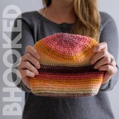 a woman holding a multicolored knitted hat