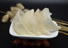 several pieces of food on a white plate with chopsticks next to the table