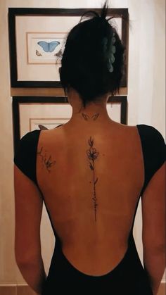 the back of a woman's body with tattoos on it