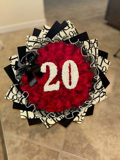 a red and black wreath with the number 20 on it that is decorated with roses