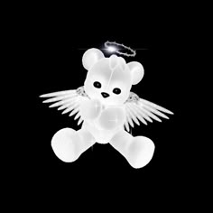 a white teddy bear with angel wings on a black background