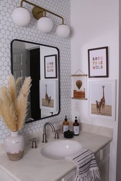 a bathroom sink with a mirror above it and pictures on the wall next to it