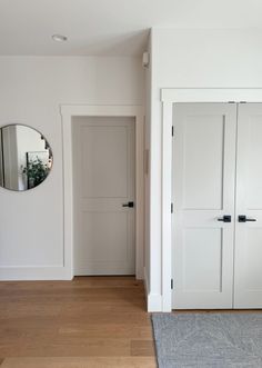 an empty room with white walls and wooden floors is shown in the foreground, there are two doors that lead to another room