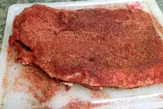 a piece of meat on a cutting board covered in seasoning