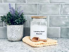 a glass jar sitting on top of a counter next to a wooden spoon and towel